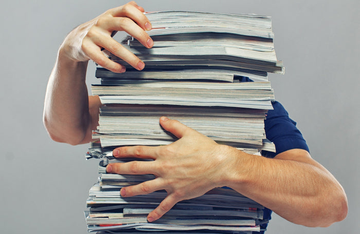 Picture of a person struggling with a stack of papers symbolizing the struggle with a complex sales stack of tools.