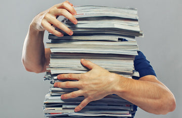 Picture of a person struggling with a stack of papers symbolizing the struggle with a complex sales stack of tools.